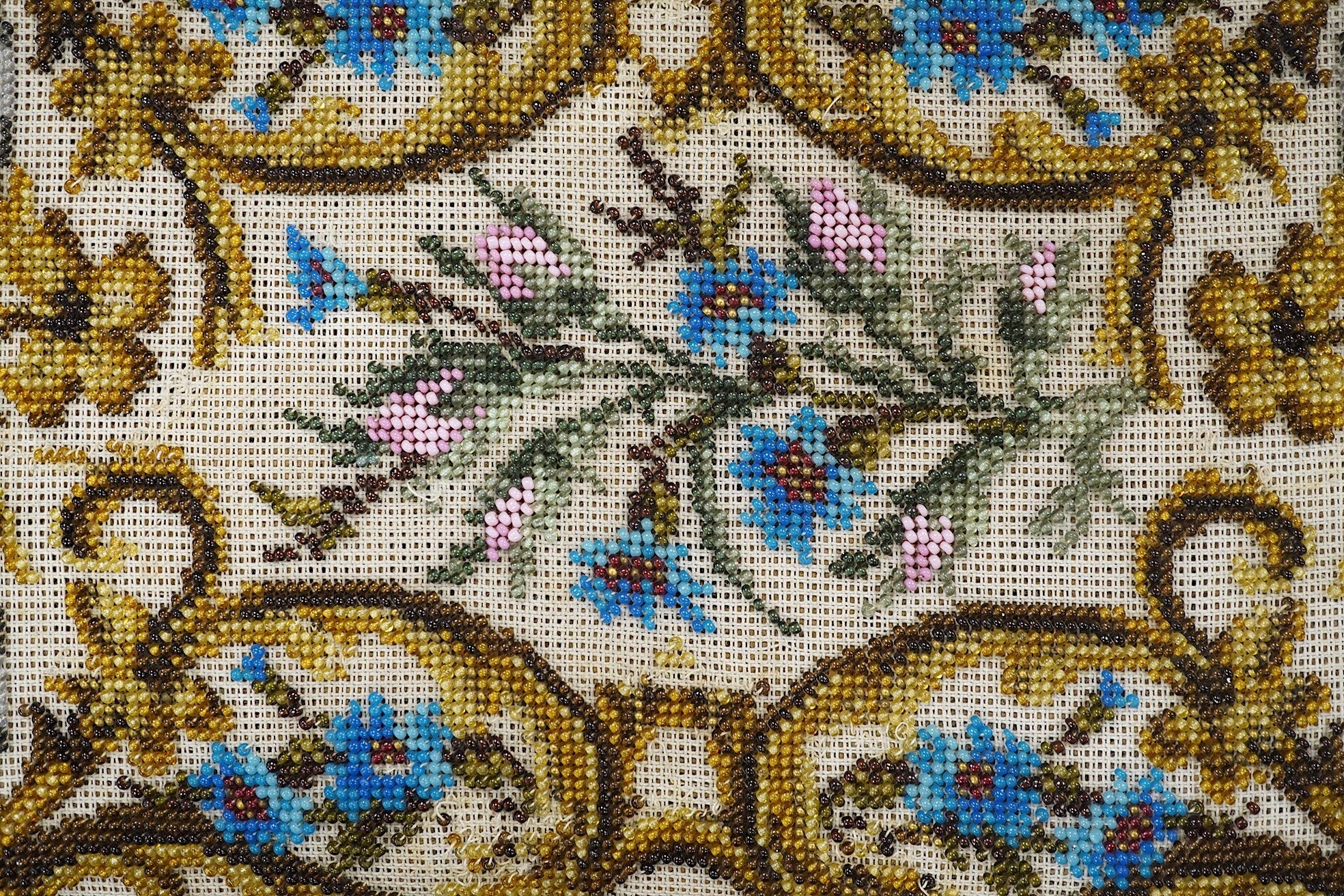 A 19th century ornately carved paw foot, Berlin beadwork upholstered footstool, the bead work a scrolling multi-coloured floral pattern, upholstered into a heavily carved frame and legs on carved paw feet, beadwork 21cm